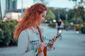 Young redhaired woman standing at night with phone