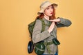 Young redhead backpacker woman hiking wearing backpack and hat over yellow background Doing time out gesture with hands,