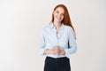 Young redhead business woman looking like professional, smiling friendly, listening client, standing over white Royalty Free Stock Photo