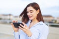 Young redhead businesswoman messaging on smartphone and laughing at outdoors