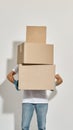 Young redhead deliveryman holding three cardboard boxes standing one on one Royalty Free Stock Photo