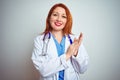 Young redhead doctor woman using stethoscope over white isolated background clapping and applauding happy and joyful, smiling Royalty Free Stock Photo