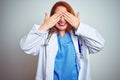 Young redhead doctor woman using stethoscope over white isolated background covering eyes with hands smiling cheerful and funny Royalty Free Stock Photo