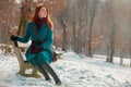 Young redhead girl in coat sitting on bench Royalty Free Stock Photo