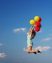 Young redhead girl with colorful balloons jumping at the blue sky Royalty Free Stock Photo