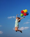 Young redhead girl with colorful balloons jumping at the blue sky Royalty Free Stock Photo