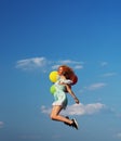 Young redhead girl with colorful balloons jumping at the blue sky Royalty Free Stock Photo