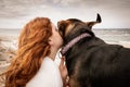 Young red haired girl kissing head of pet Huntaway dog, New Zealand