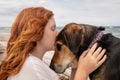 Young red haired girl kissing head of pet Huntaway dog, New Zealand