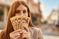 Young redhead girl smiling happy covering face with hungarian forint banknotes at the city