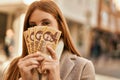 Young redhead girl smiling happy covering face with hungarian forint banknotes at the city