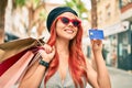 Young redhead girl wearing french style holding shopping bags  and showing credit card at the city Royalty Free Stock Photo