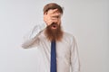 Young redhead irish businessman standing over isolated white background peeking in shock covering face and eyes with hand, looking Royalty Free Stock Photo