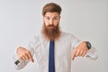 Young redhead irish businessman standing over isolated white background Pointing down looking sad and upset, indicating direction Royalty Free Stock Photo