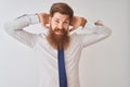 Young redhead irish businessman standing over isolated white background relaxing and stretching, arms and hands behind head and Royalty Free Stock Photo