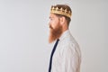 Young redhead irish businessman wearing crown king over isolated white background looking to side, relax profile pose with natural Royalty Free Stock Photo