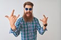 Young redhead irish man wearing casual shirt and sunglasses over isolated white background shouting with crazy expression doing Royalty Free Stock Photo