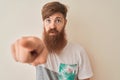 Young redhead irish man wearing t-shirt standing over isolated white background pointing with finger to the camera and to you,