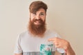 Young redhead irish man wearing t-shirt standing over isolated white background with surprise face pointing finger to himself Royalty Free Stock Photo