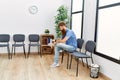 Young redhead man bored sitting on the chair at waiting room Royalty Free Stock Photo