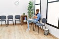 Young redhead man bored sitting on the chair at waiting room Royalty Free Stock Photo