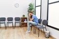 Young redhead man bored sitting on the chair at waiting room Royalty Free Stock Photo