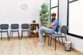 Young redhead man bored sitting on the chair at waiting room Royalty Free Stock Photo