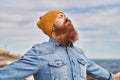 Young redhead man breathing at seaside