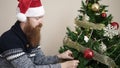 Young redhead man decorating christmas tree at home Royalty Free Stock Photo