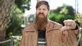 Young redhead man doing negative sign with thumb down at park Royalty Free Stock Photo