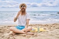 Young redhead man eating ice cream sitting on the towel at the beach Royalty Free Stock Photo