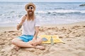 Young redhead man eating ice cream sitting on the towel at the beach Royalty Free Stock Photo