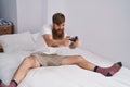 Young redhead man playing video game sitting on bed at bedroom Royalty Free Stock Photo