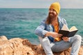 Young redhead man smiling confident reading book at seaside Royalty Free Stock Photo