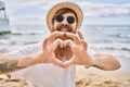 Young redhead man smiling happy doing heart symbol with hands at the beach Royalty Free Stock Photo
