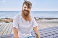 Young redhead man smiling happy sitting on the bench at the beach Royalty Free Stock Photo