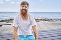 Young redhead man smiling happy sitting on the bench at the beach Royalty Free Stock Photo