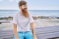 Young redhead man smiling happy sitting on the bench at the beach Royalty Free Stock Photo