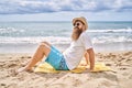 Young redhead man smiling happy sitting on the towel at the beach Royalty Free Stock Photo