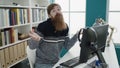 Young redhead man student using computer with unsure gesture at library university Royalty Free Stock Photo