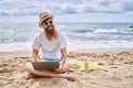 Young redhead man using laptop sitting on the towel at the beach Royalty Free Stock Photo