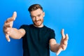 Young redhead man wearing casual black t shirt looking at the camera smiling with open arms for hug Royalty Free Stock Photo