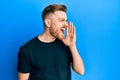 Young redhead man wearing casual black t shirt shouting and screaming loud to side with hand on mouth Royalty Free Stock Photo