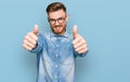 Young redhead man wearing casual denim shirt approving doing positive gesture with hand, thumbs up smiling and happy for success Royalty Free Stock Photo