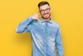 Young redhead man wearing casual denim shirt smiling doing phone gesture with hand and fingers like talking on the telephone Royalty Free Stock Photo