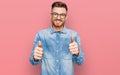 Young redhead man wearing casual denim shirt success sign doing positive gesture with hand, thumbs up smiling and happy Royalty Free Stock Photo