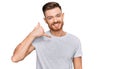 Young redhead man wearing casual grey t shirt smiling doing phone gesture with hand and fingers like talking on the telephone Royalty Free Stock Photo