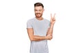 Young redhead man wearing casual grey t shirt smiling with happy face winking at the camera doing victory sign Royalty Free Stock Photo