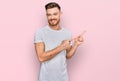 Young redhead man wearing casual grey t shirt smiling and looking at the camera pointing with two hands and fingers to the side Royalty Free Stock Photo