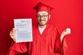 Young redhead man wearing graduation robe showing passed exam screaming proud, celebrating victory and success very excited with Royalty Free Stock Photo